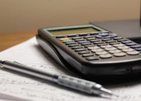 A detailed view of a calculator and pen resting on mathematical notes, ideal for educational and financial themes.